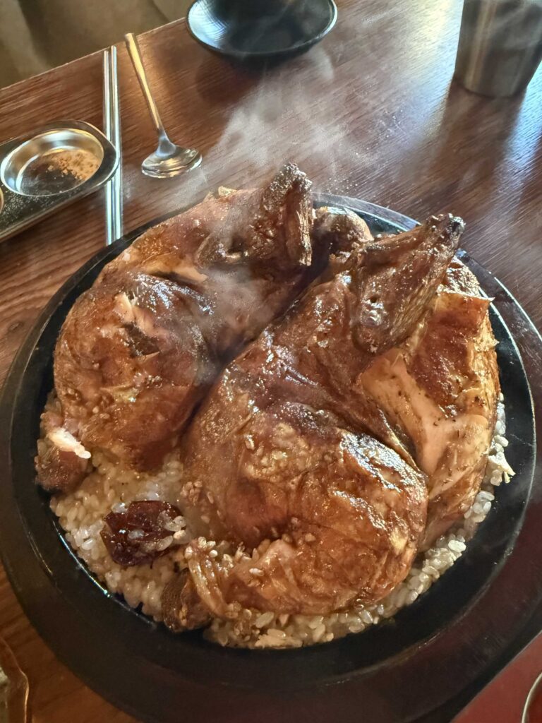 Whole charcoal-roasted nurungji chicken steaming on hot plate in Hanam Misa