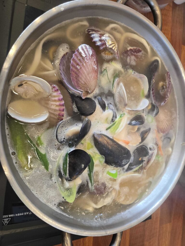 Top-down view of Park Seung-gwang Haemul Kalguksu pot at the beginning of cooking