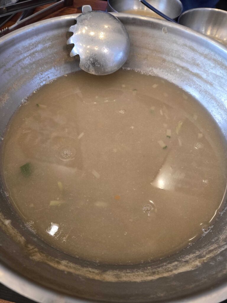 Remaining rich broth in the pot after eating all seafood at Park Seung-gwang Kalguksu