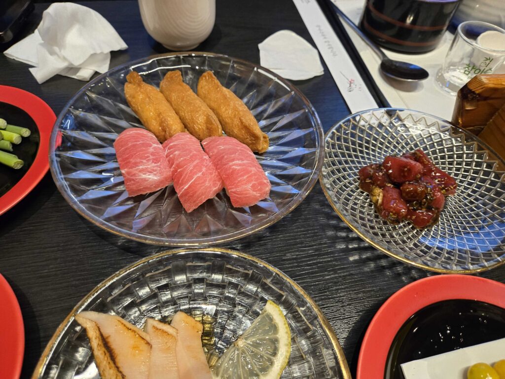 inari sushi with tuna topping alongside banchan side dishes