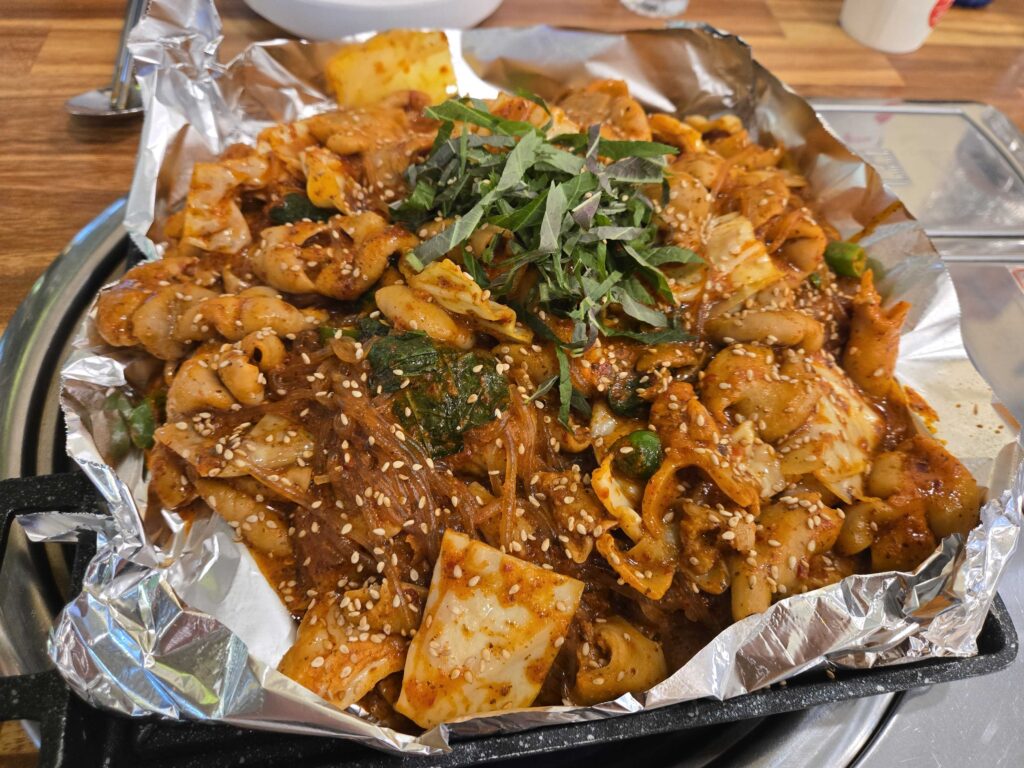 Korean yachae intestine dish with tteok rice cakes, glass noodles, and perilla leaves