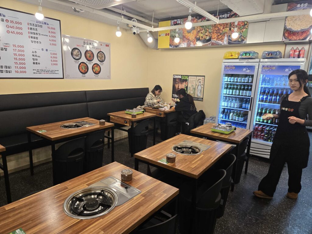 Taeyang Gopchang restaurant interior with wooden tables and built-in burners near Gundae Station