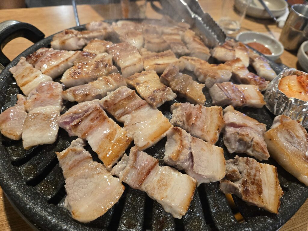 Fresh samgyeopsal pork belly grilling on a Korean BBQ stone grill at Mongttang Saenggogi Seongsu