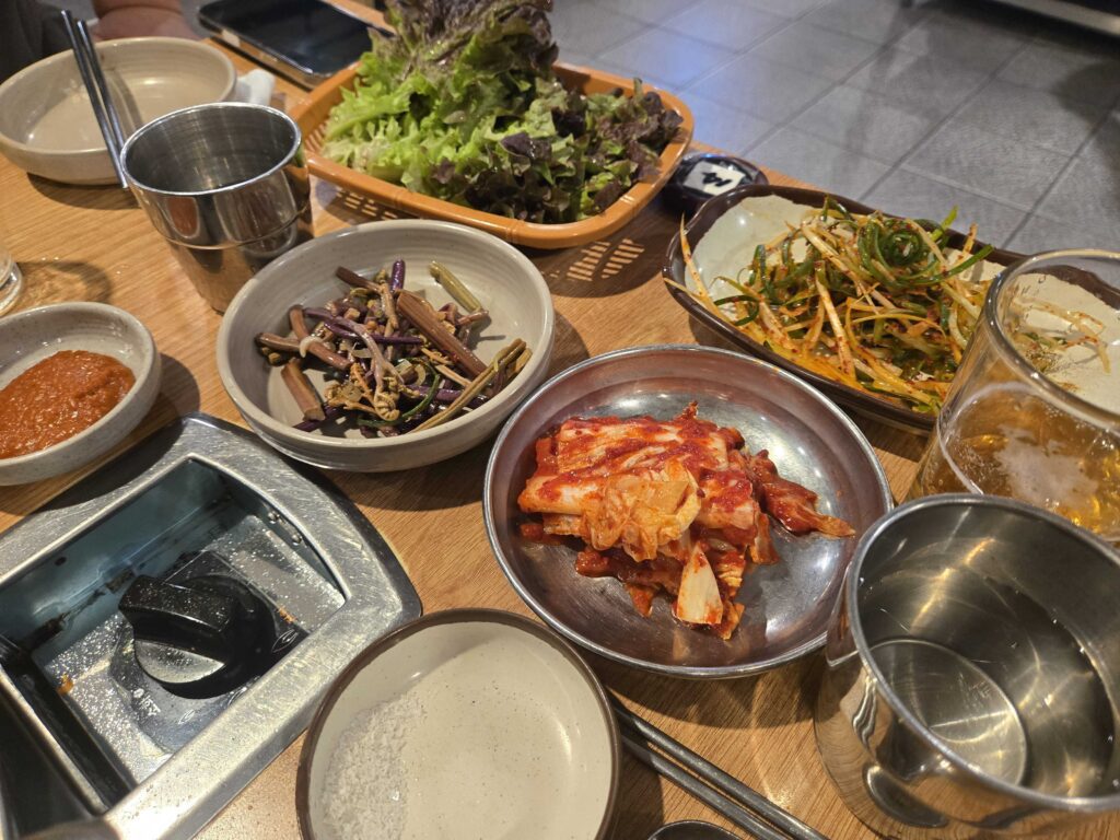 Lettuce basket, kimchi, seasoned greens and pa-chae on the table at Mongttang Saenggogi
