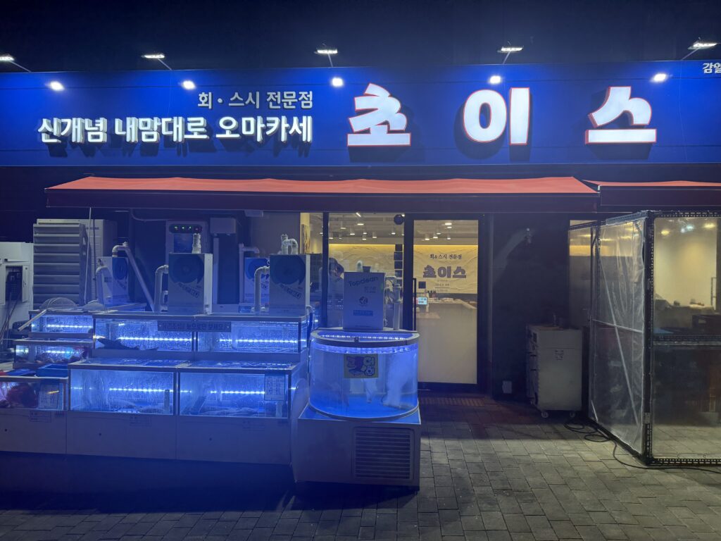 The Choice storefront at night, with fish tanks by the door