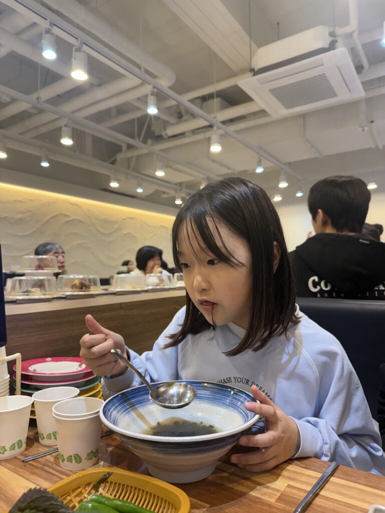Girl eating miso soup noodles Gamil Choice Hanam rotating sushi