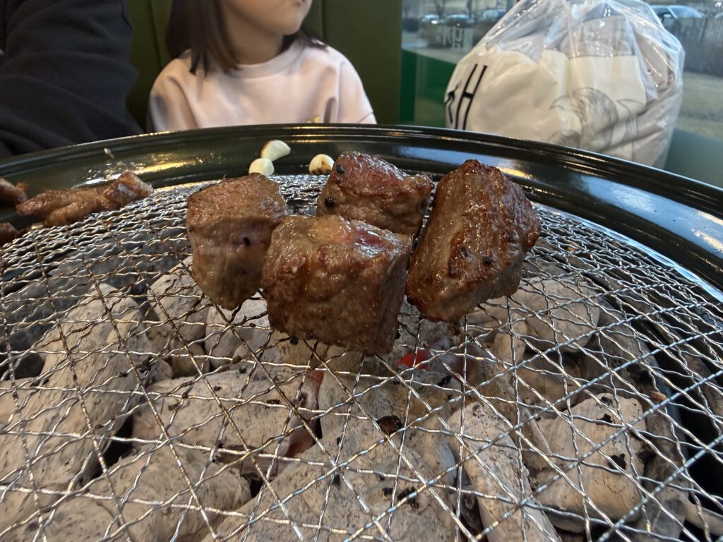 Perfectly grilled golden-brown beef pieces sizzling on charcoal grill