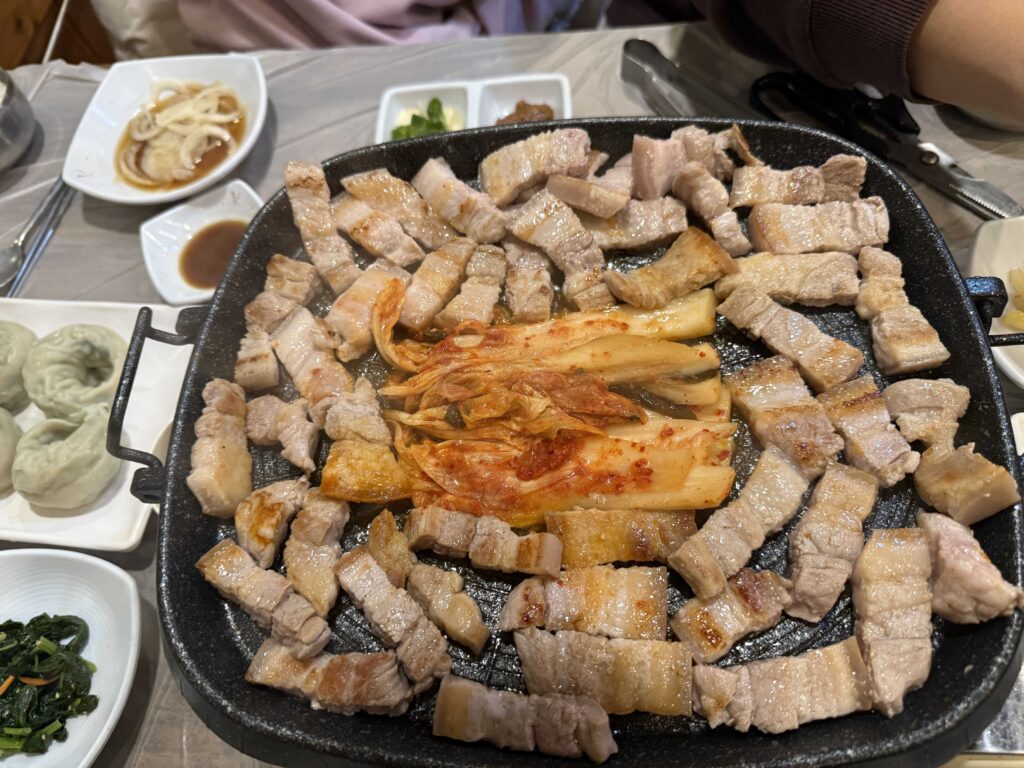 Pork belly and kimchi cooking on grill at Mannajeong Wonju restaurant