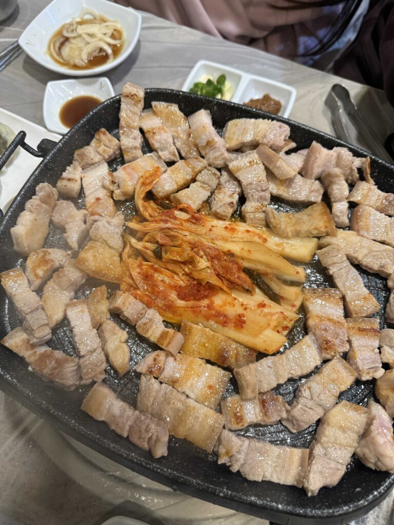 Samgyeopsal pork belly sizzling on table grill at Mannajeong Korean BBQ