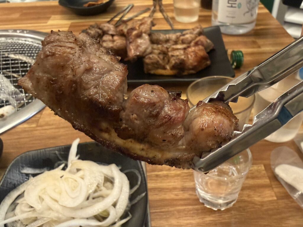 Charred pork ribs on a Korean BBQ grill with caramelized onion slices