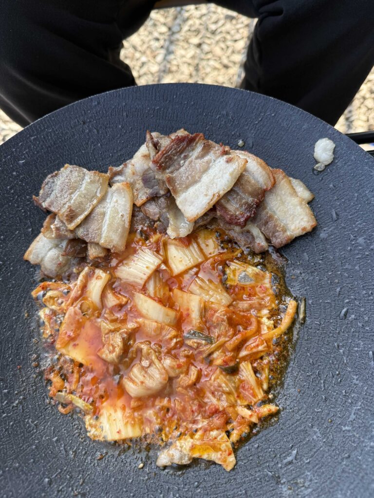 Korean BBQ pork belly and kimchi cooking at the campsite