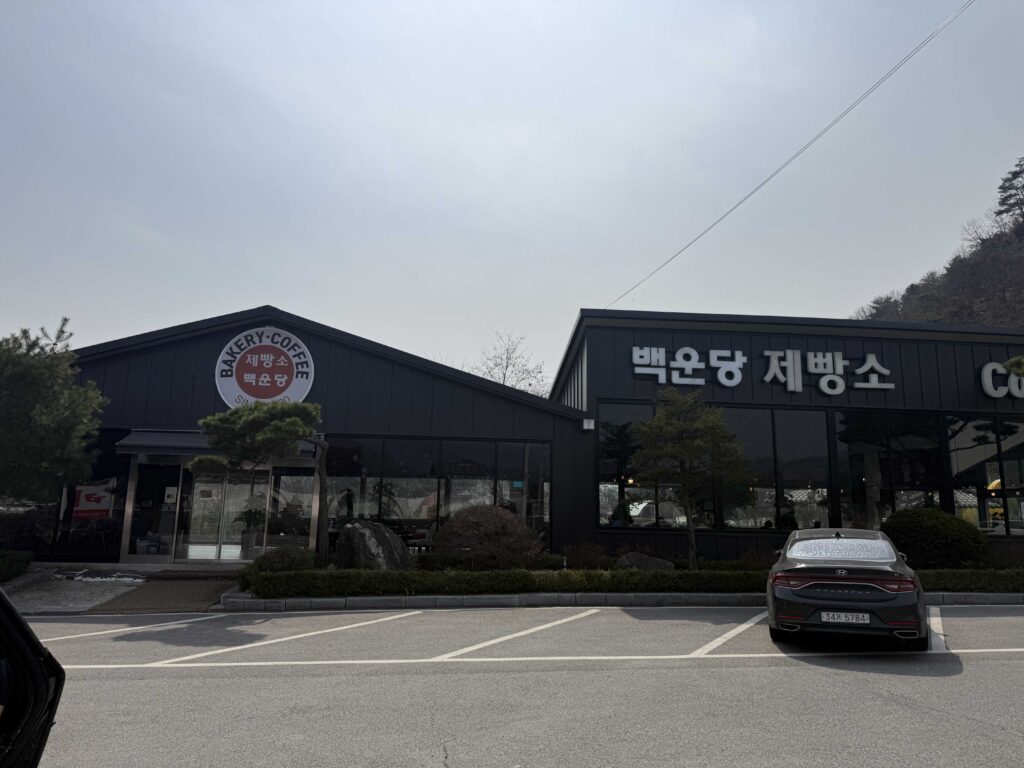 Exterior of Baegundang Bakery Pocheon building with dark wooden siding and mountain backdrop