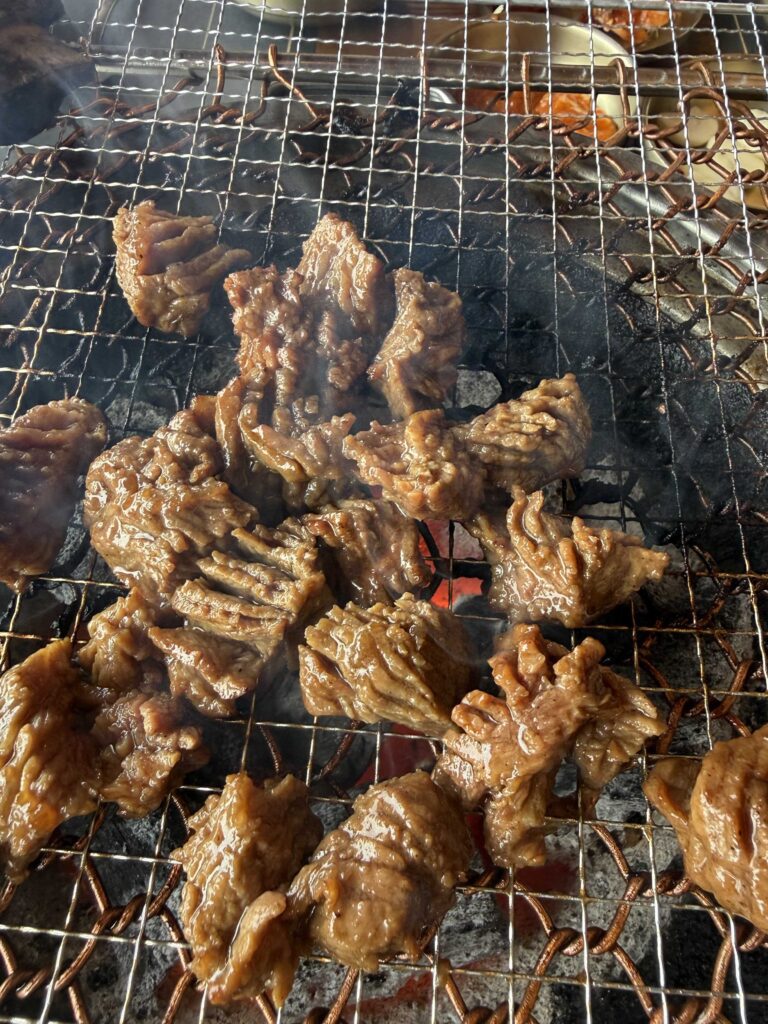 Boneless Idong galbi pieces curling on the charcoal grill