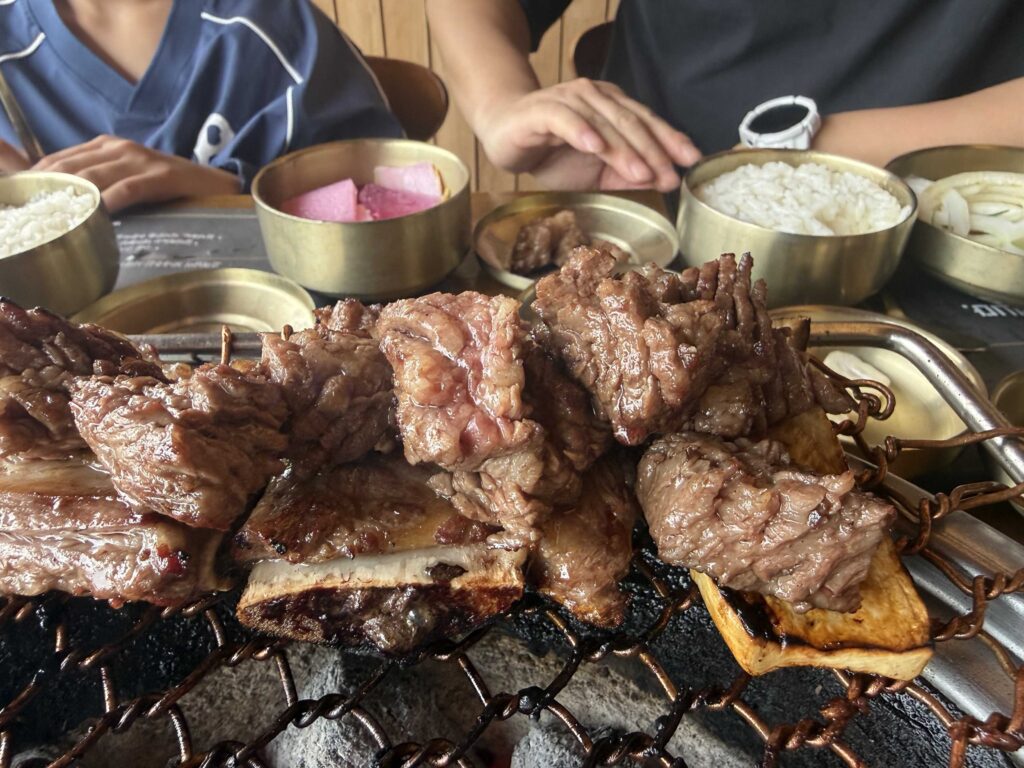 Child eating galbi with rice bowls and banchan