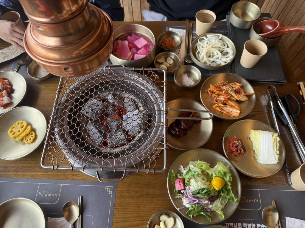 Full BBQ table with charcoal grill and Korean banchan side dishes