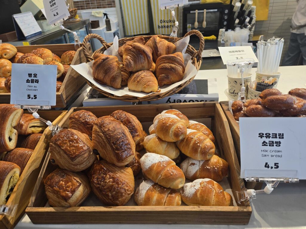 Okuku Bakery bread display with price signs showing salt bread croissant and chocolate options