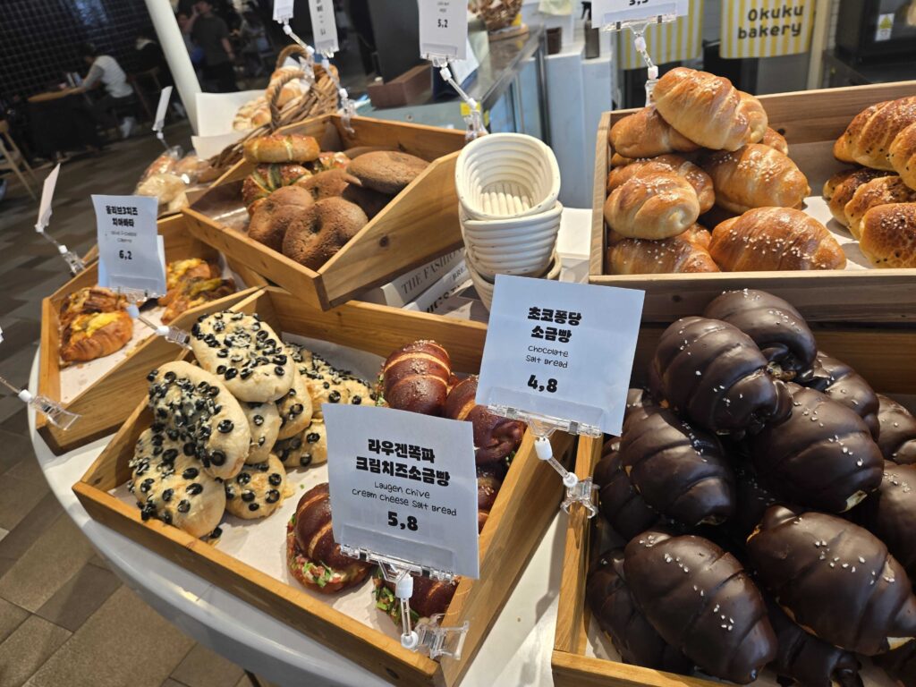 Okuku Bakery display showing savory bread options including egg shrimp items and specialty croissants