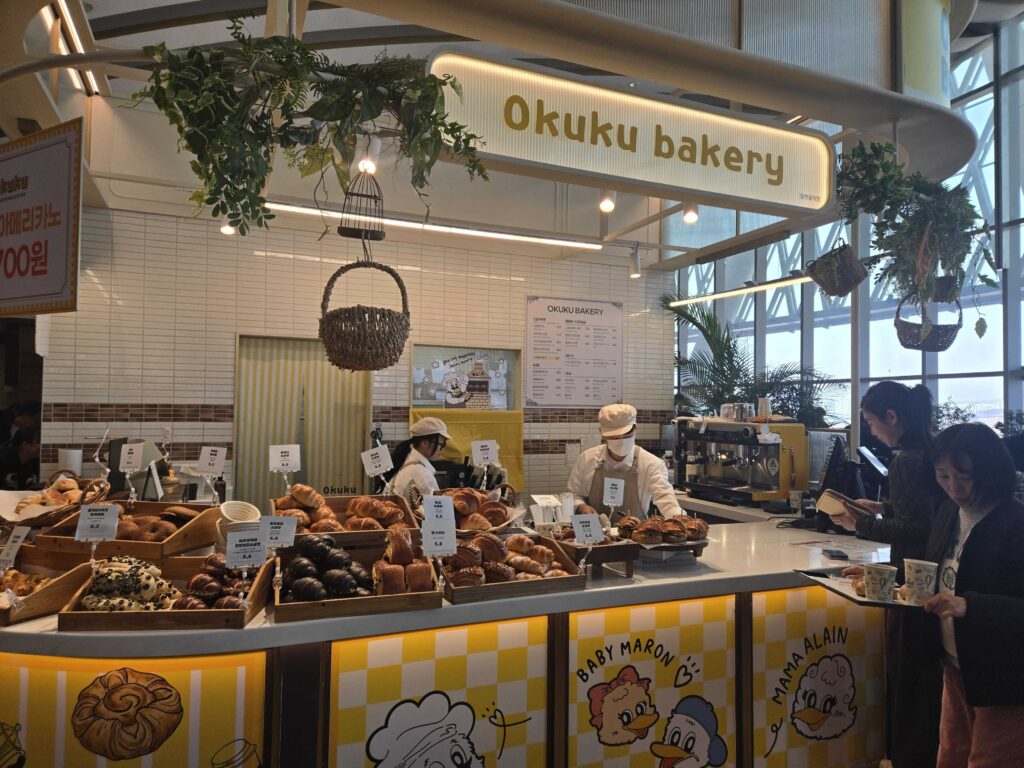 Okuku Bakery at Starfield Hanam exterior view with yellow counter and breads on display