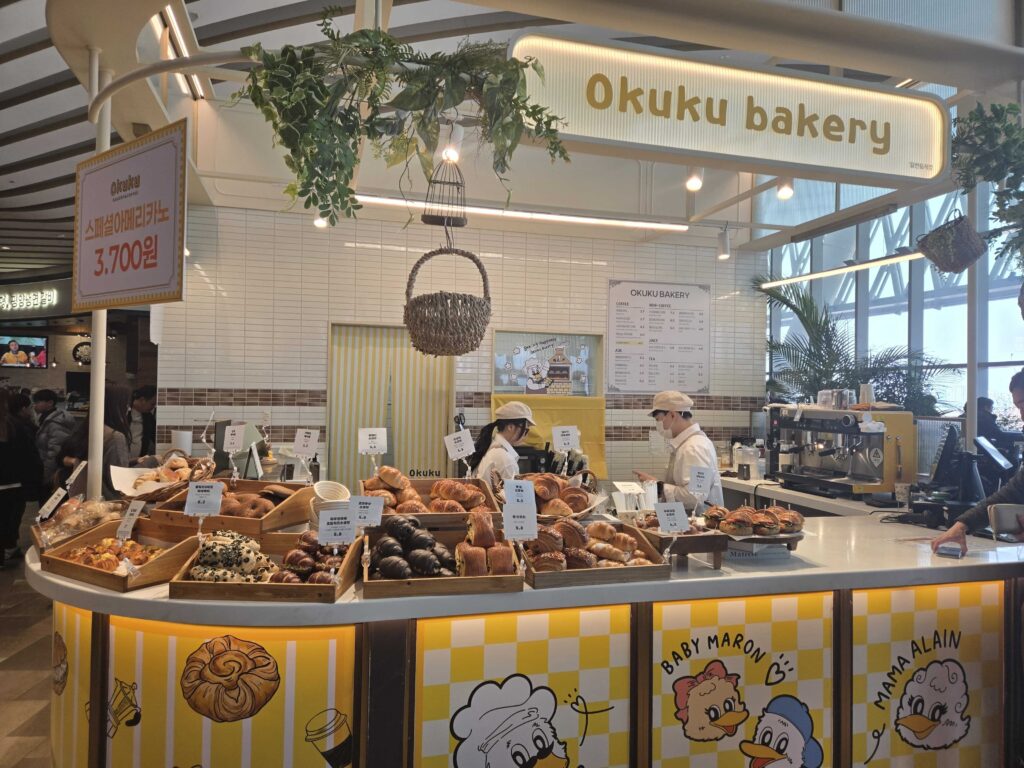 Okuku Bakery Starfield Hanam front counter with duck mascot illustrations and yellow checkered panels