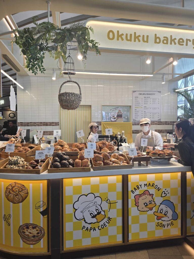 Okuku Bakery bakers in white uniforms working behind the counter at Starfield Hanam