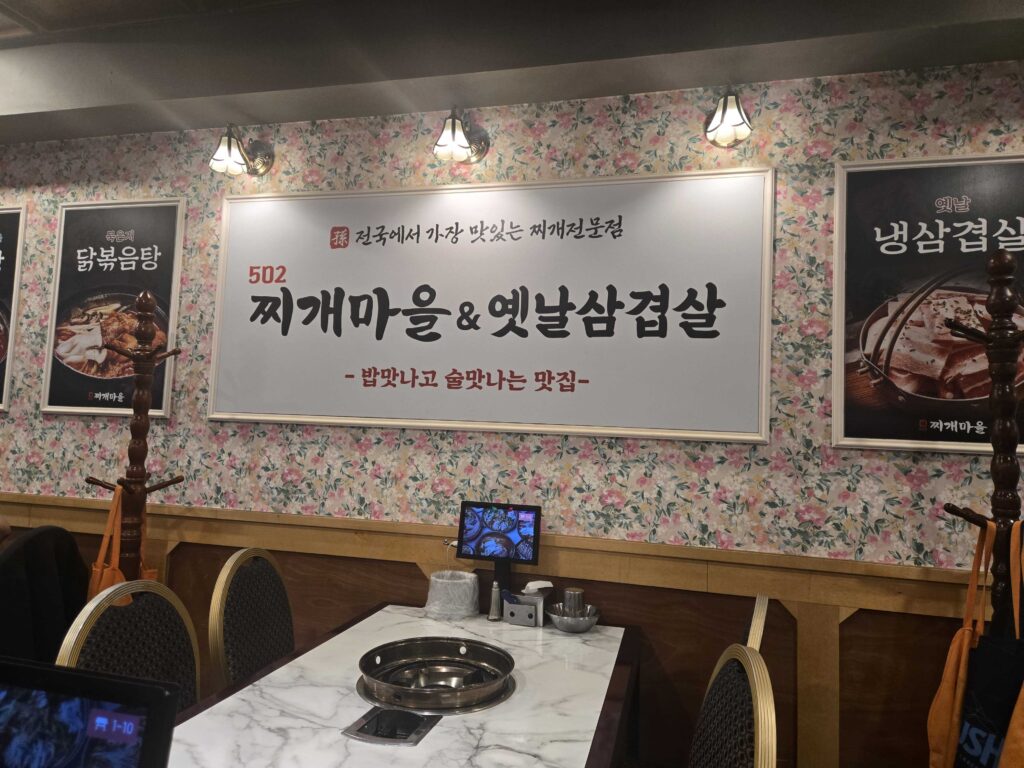 502 Jjigae Maeul Konkuk University restaurant interior sign showing the restaurant name and floral wallpaper