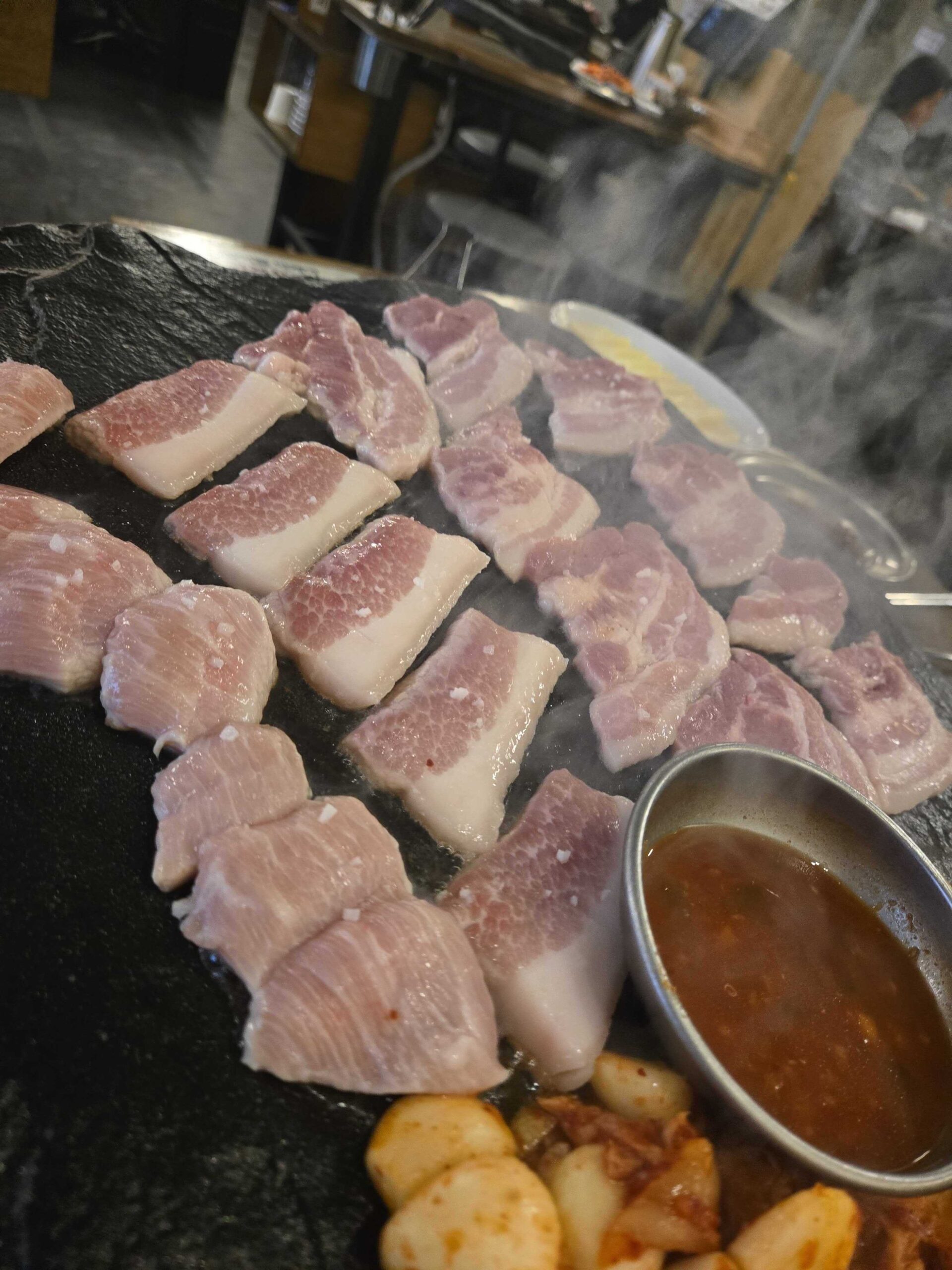 Pork slices cooking on the stone plate at Seokam in Seongsu
