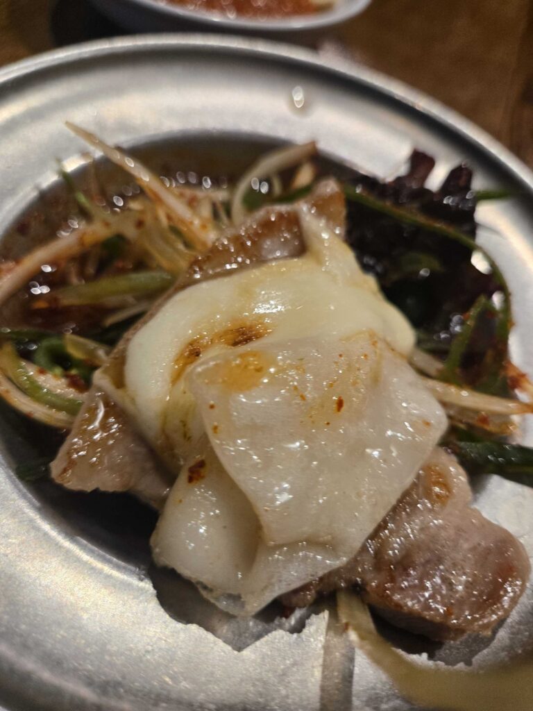 Grilled samgyeopsal wrapped in a leaf with grilled garlic and green onion — Korean BBQ ssam