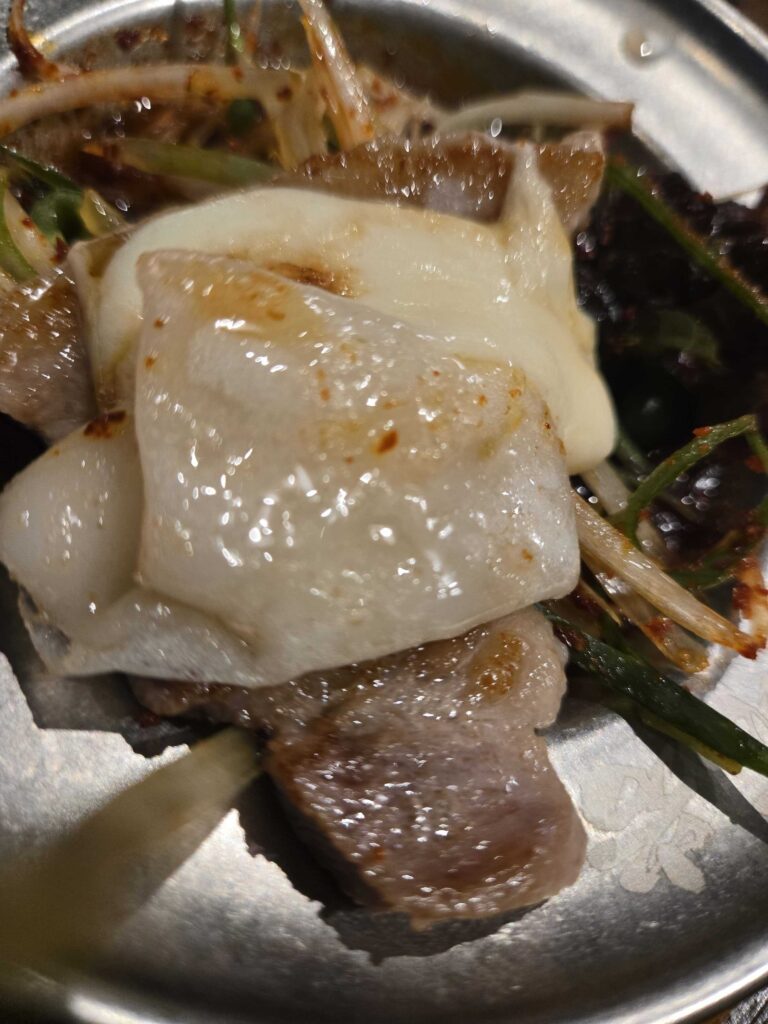 Grilled samgyeopsal with garlic and pa-chae green onion on a stone plate