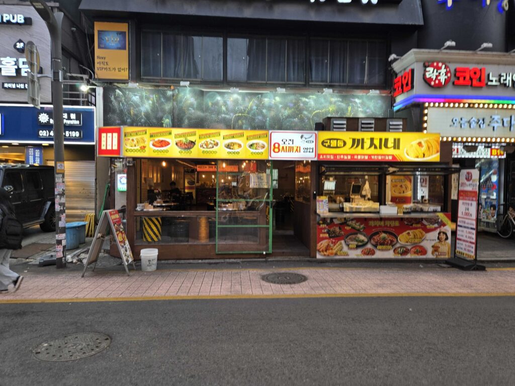 Korean restaurant entrance with yellow signboard at night near Kondae