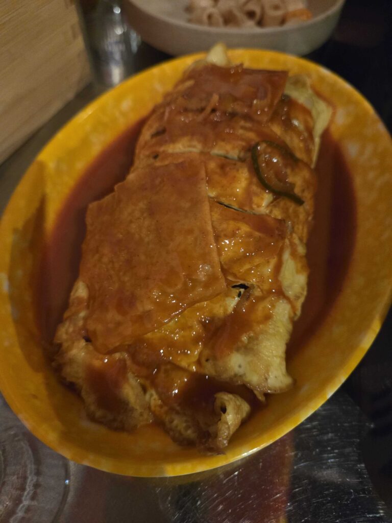 Egg roll kimbap at Guwoldong Kkachine served in yellow bowl with sauce