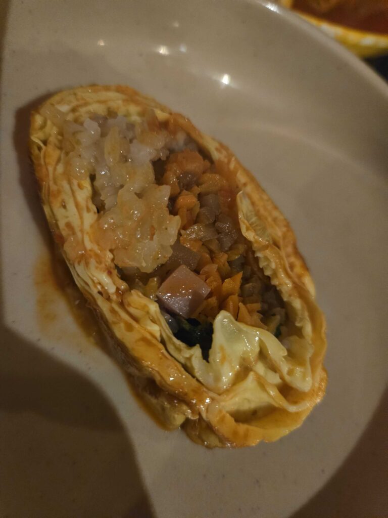 Cross section of egg roll kimbap showing rice ham and vegetable filling inside egg wrap