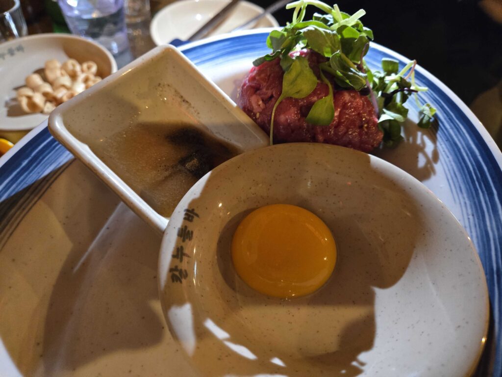 Yukhoe Korean beef tartare with raw egg yolk sesame oil and microgreens at Guwoldong Kkachine