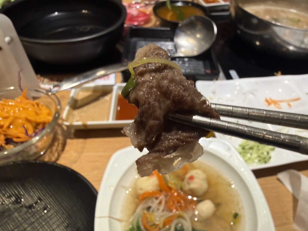 A slice of cooked beef lifted from the broth