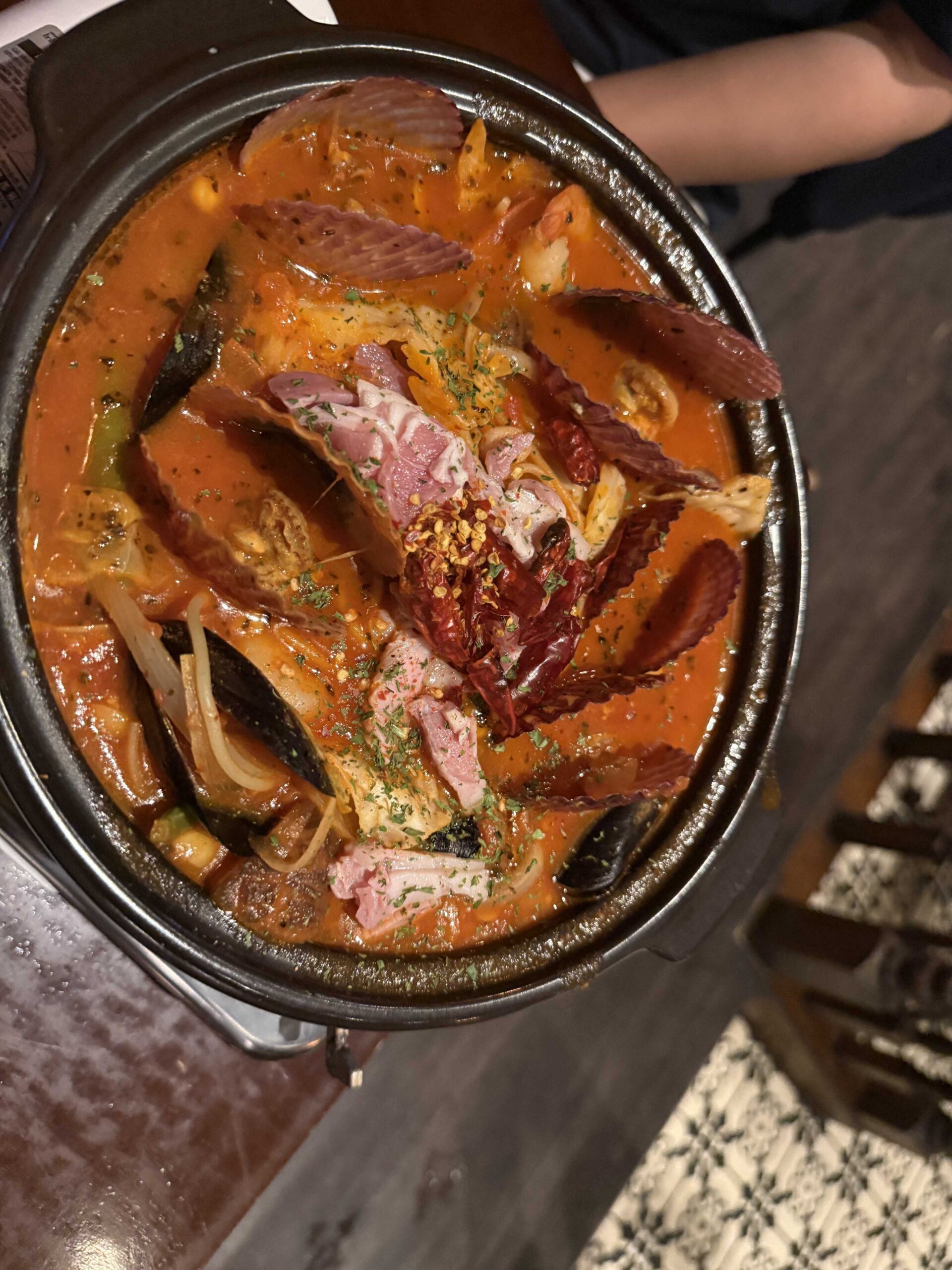 Top-down view of tomato haejang pastang with mussels bacon and dried chili at Geumbyeol Maekju Bangi