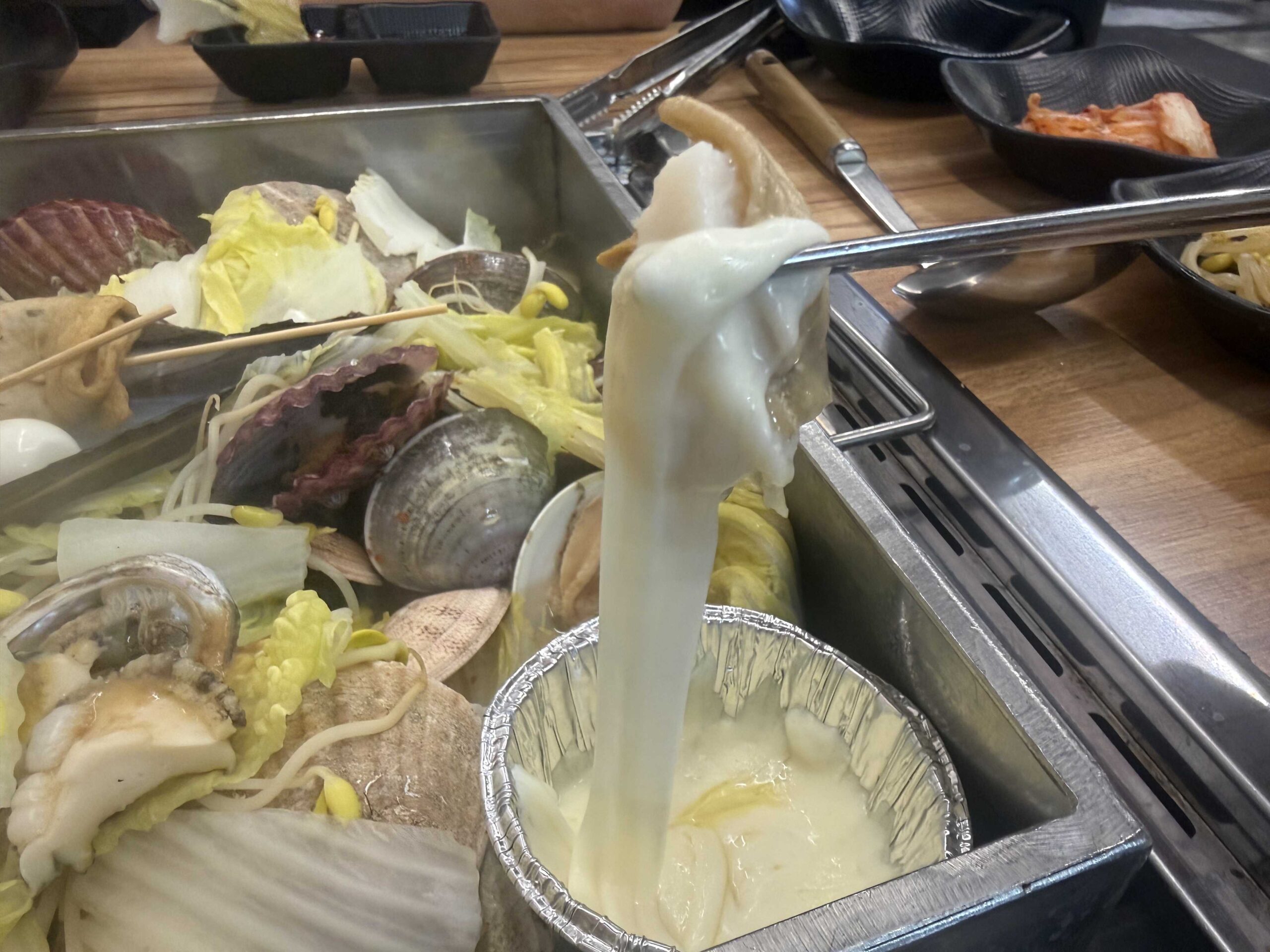 Melted mozzarella cheese stretching off a scallop at Jjimagi Jamsil Bangi