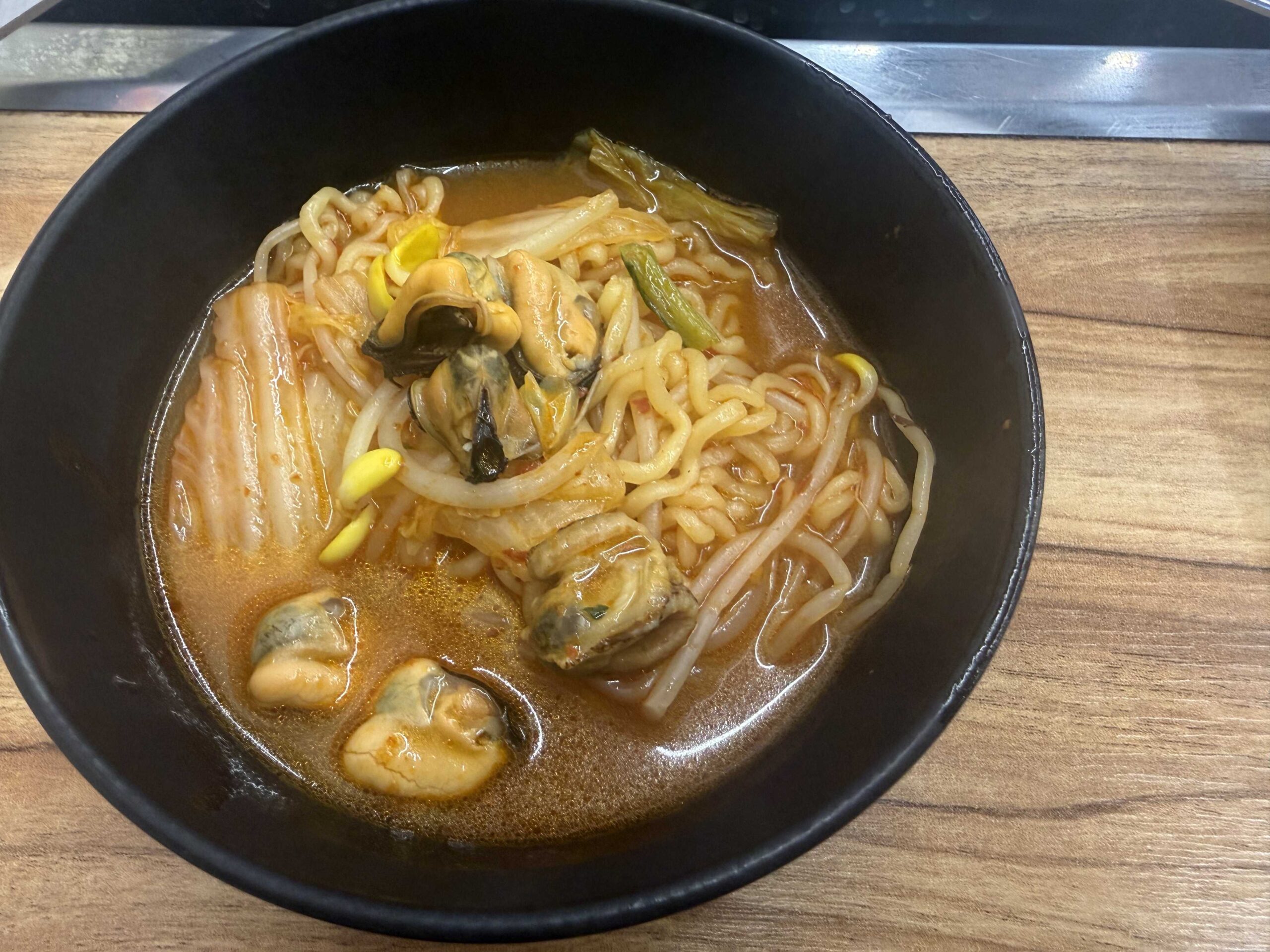 Jjimagi Jamsil Bangi haejang ramyeon with mussels, abalone, and bean sprouts in spicy broth