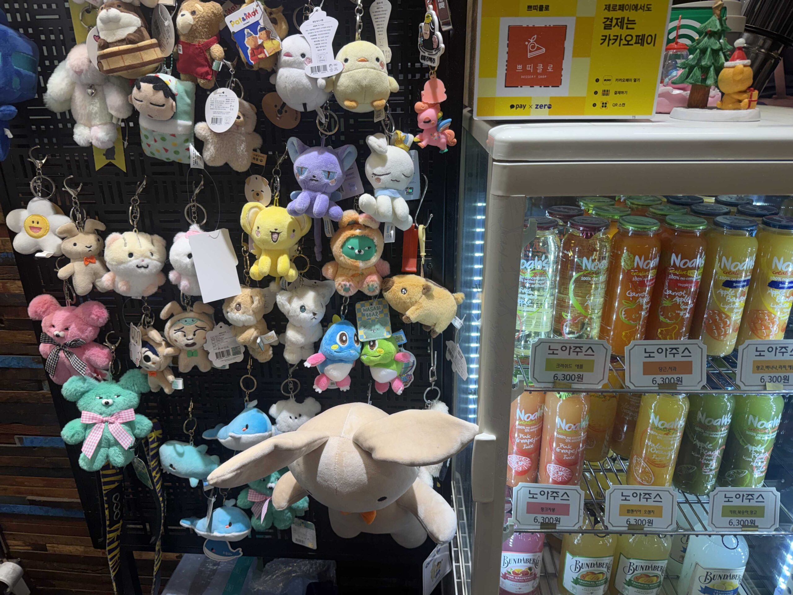 Petit Chlo Jamsil plushie keychain display wall beside juice refrigerator