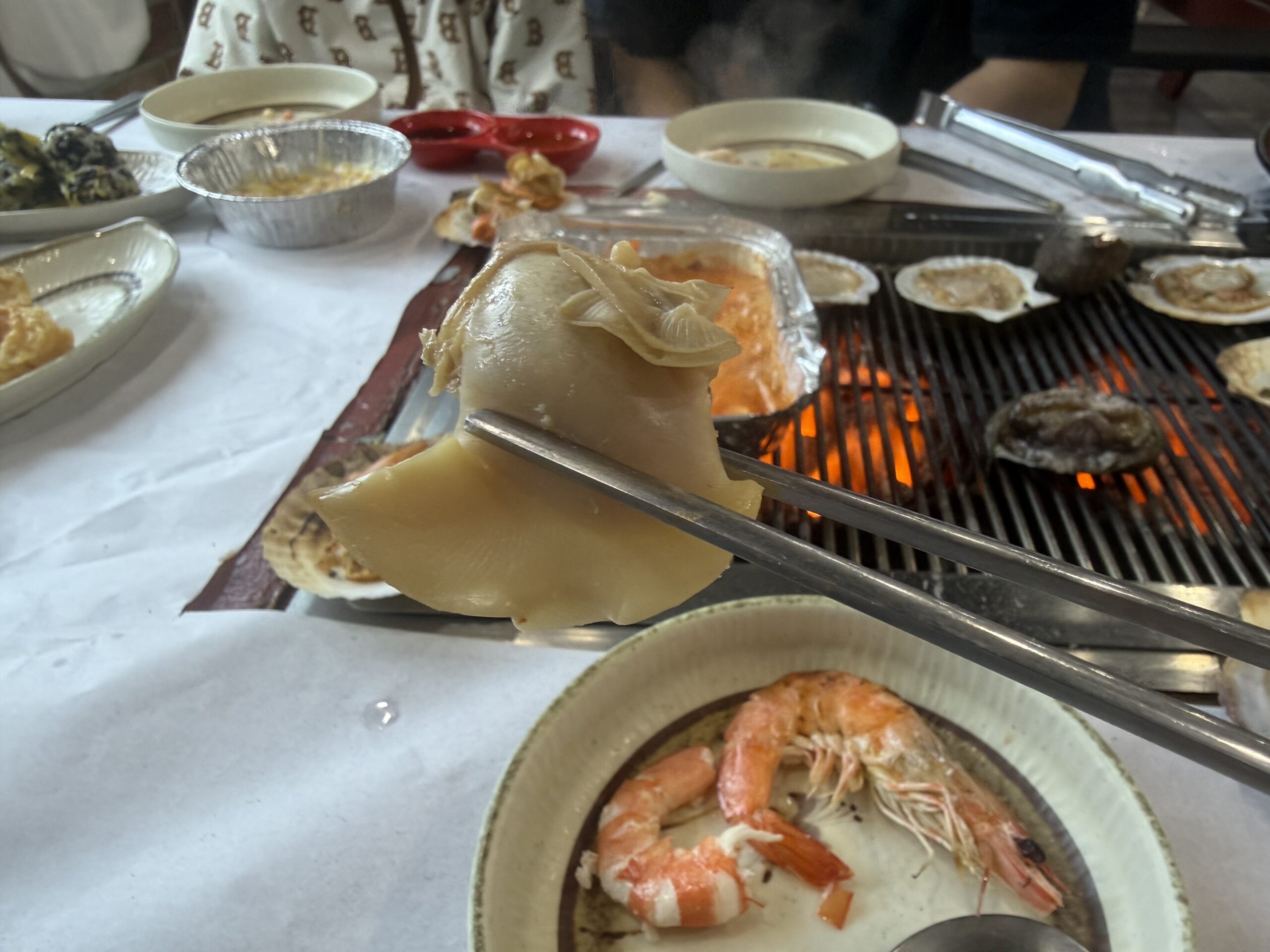 Scallops and abalone cooking on charcoal grill at Pungnyeon Hwesenta
