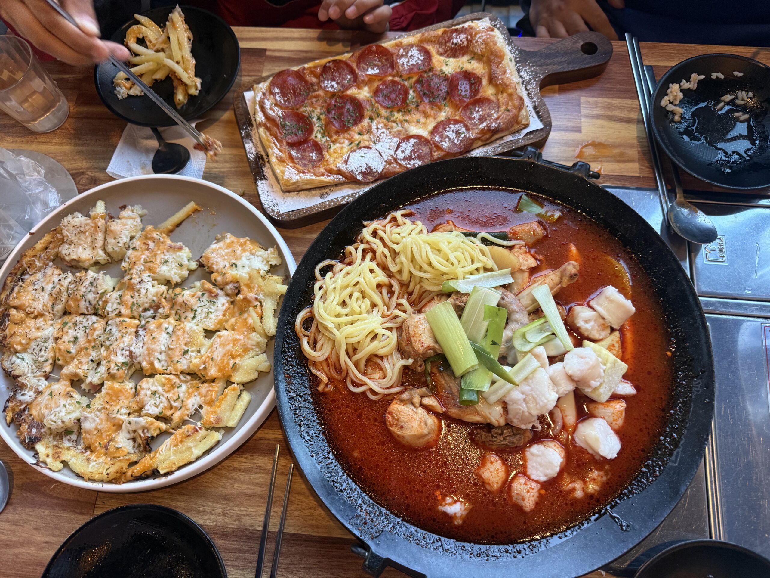 Full table spread at Pocha Cheonguk Hanam with gopdori-tang, pizza, and gamjajeon
