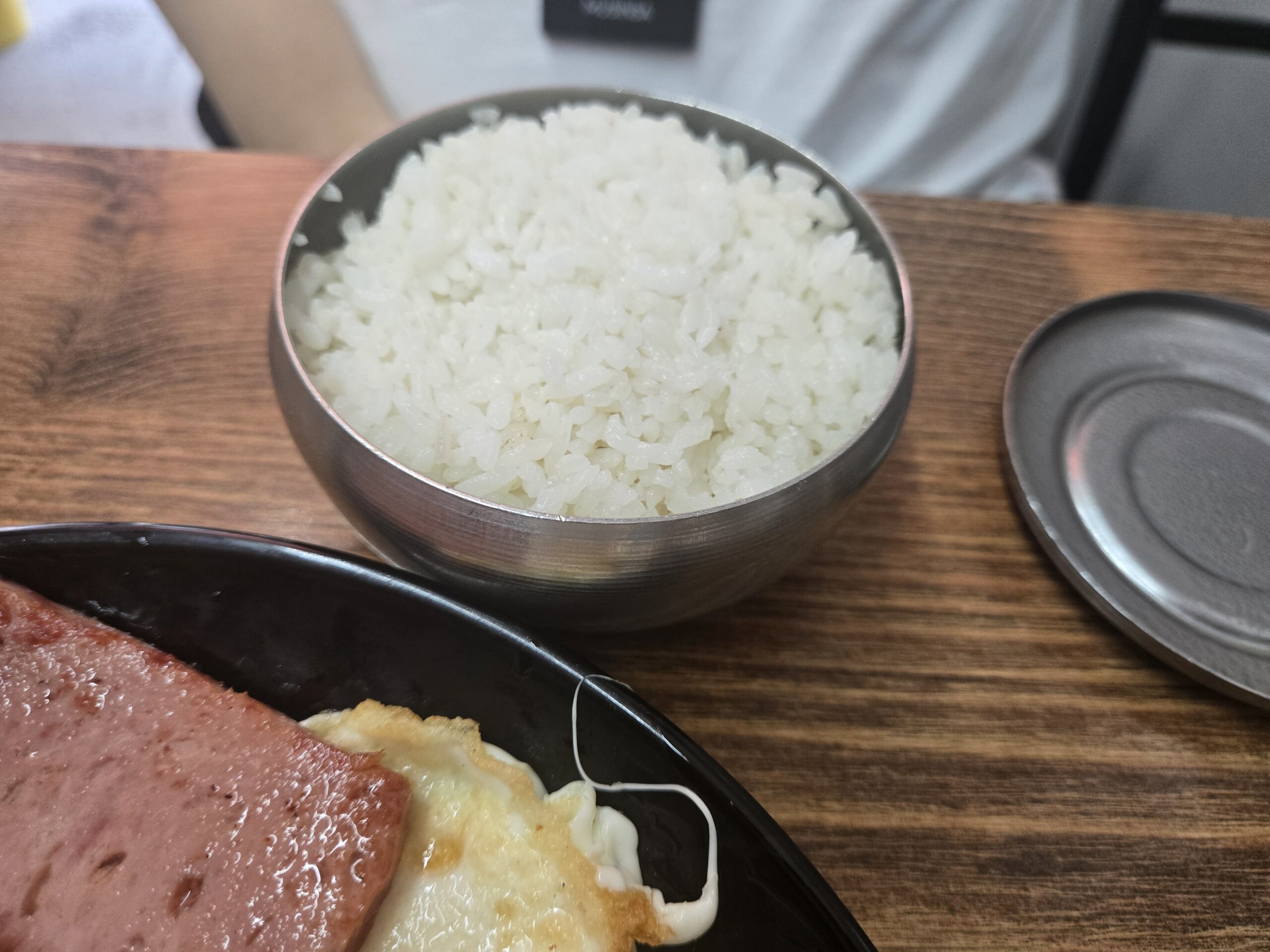 Stainless steel rice bowl beside spam plate Dalnimine