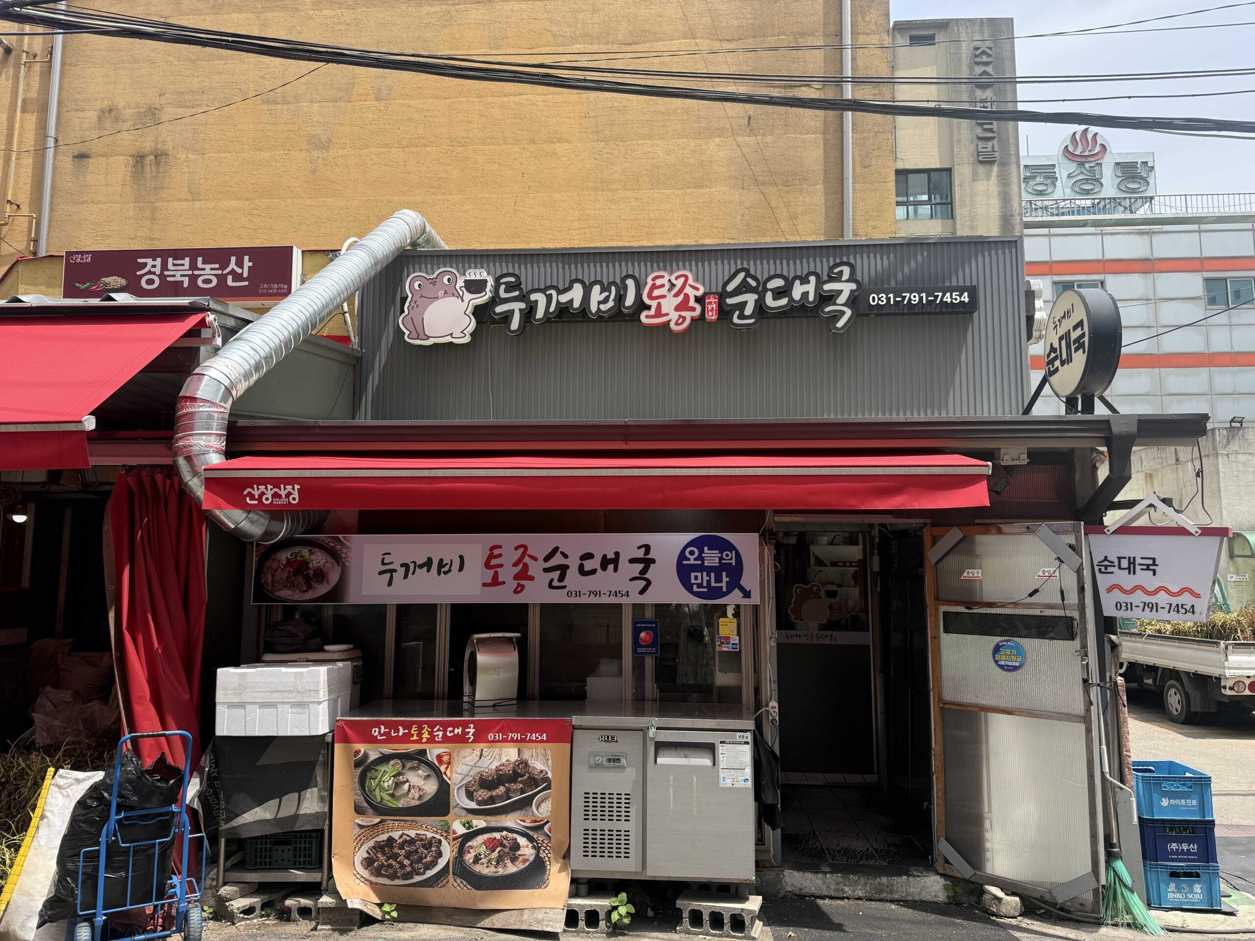 Dukkeobi Sundae Guk Hanam exterior with toad mascot sign at Sinjang Market entrance