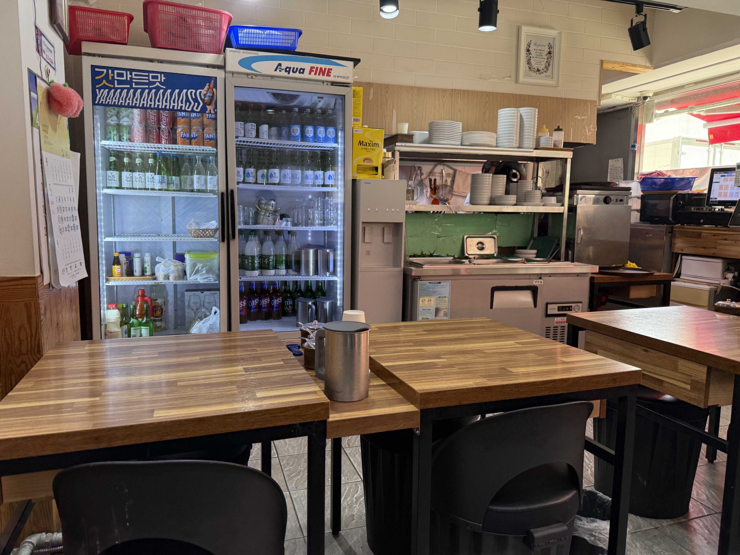 Beverage fridge and empty wooden tables at Dukkeobi Sundae Guk Hanam