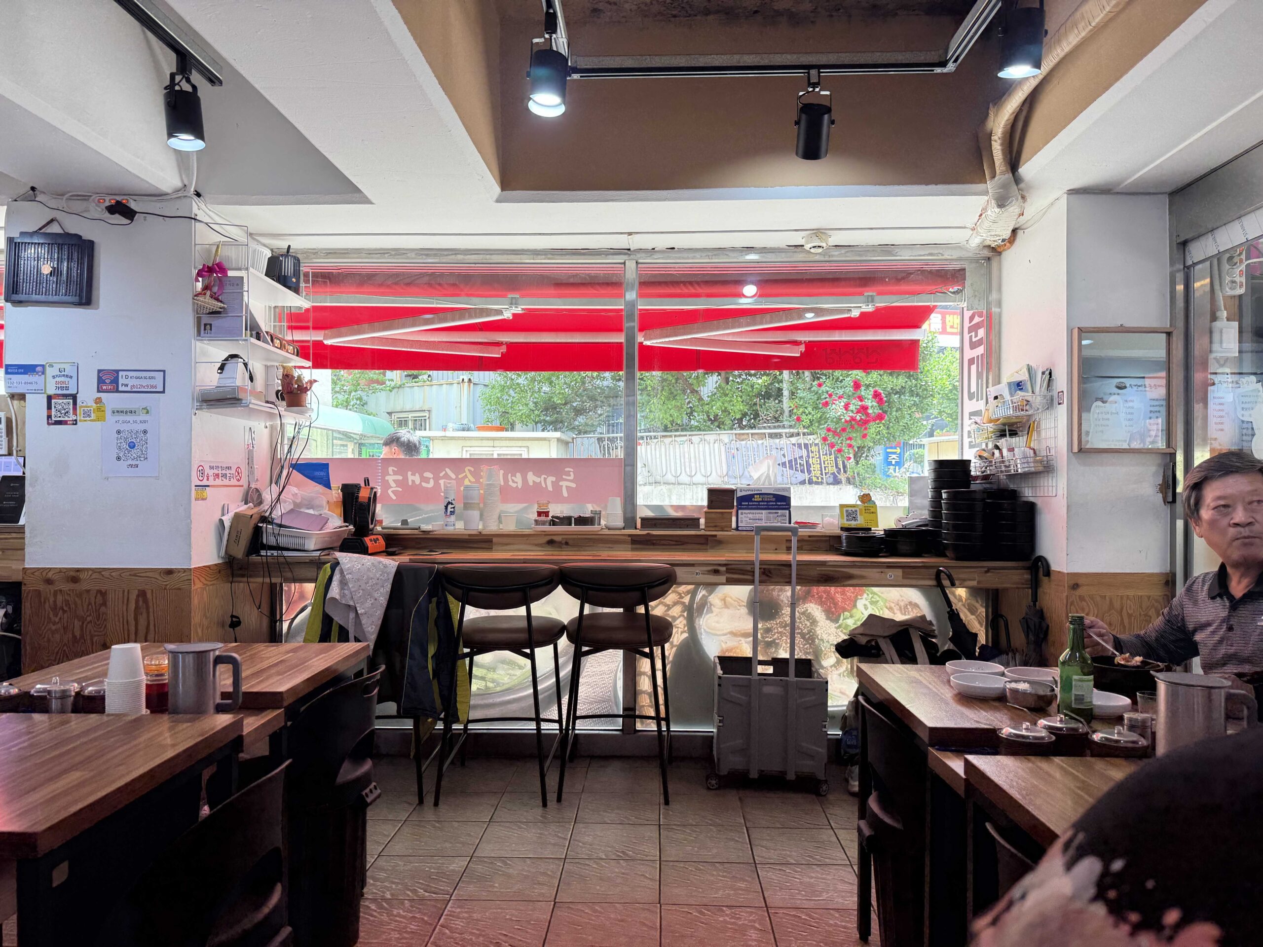 Interior wide shot at Dukkeobi Sundae Guk Hanam with old Korean signs and wooden floor