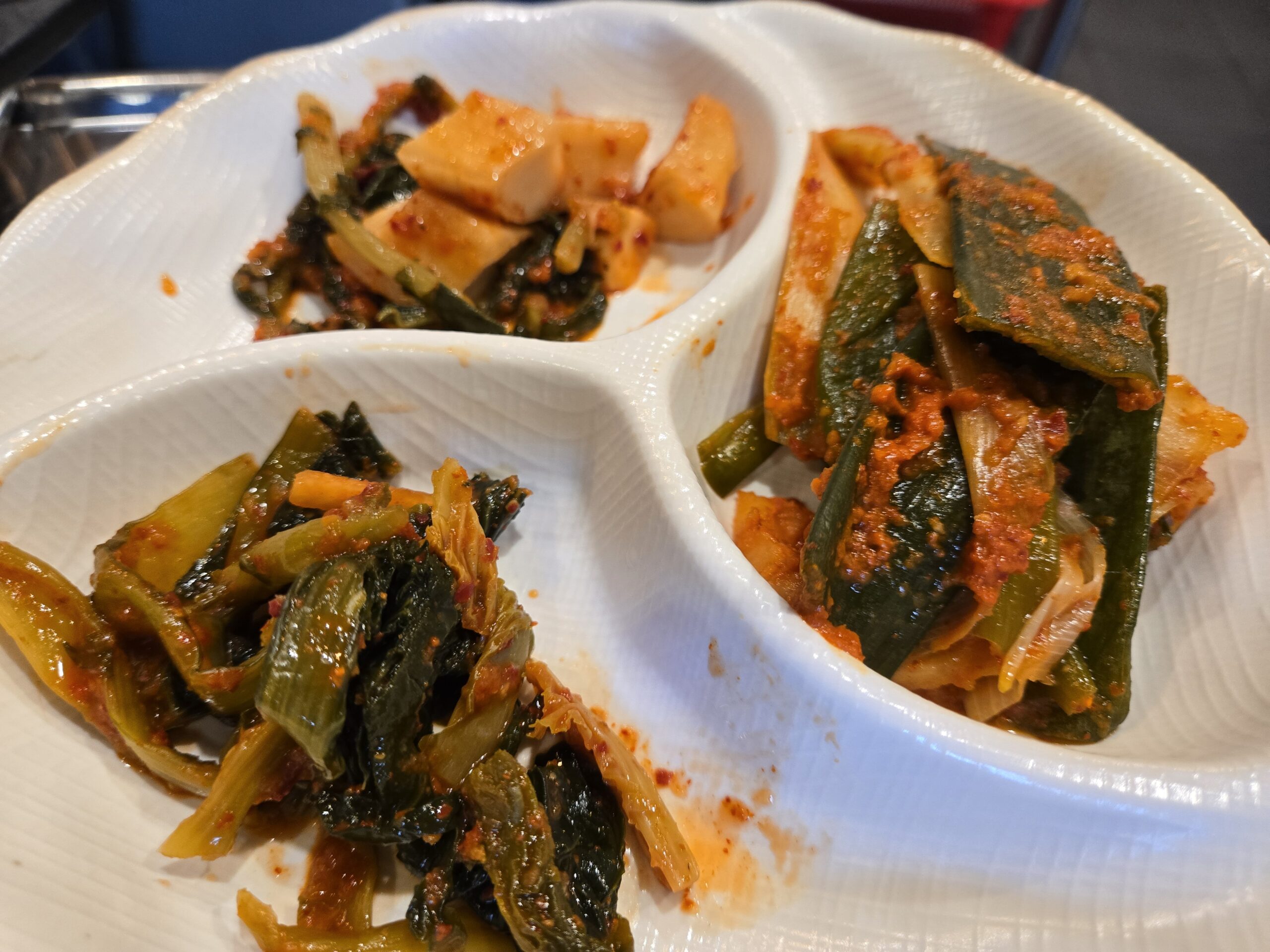 Three-compartment banchan plate with kkakdugi musaengchae and gat-kimchi at Jinseong Hanu Gopchang