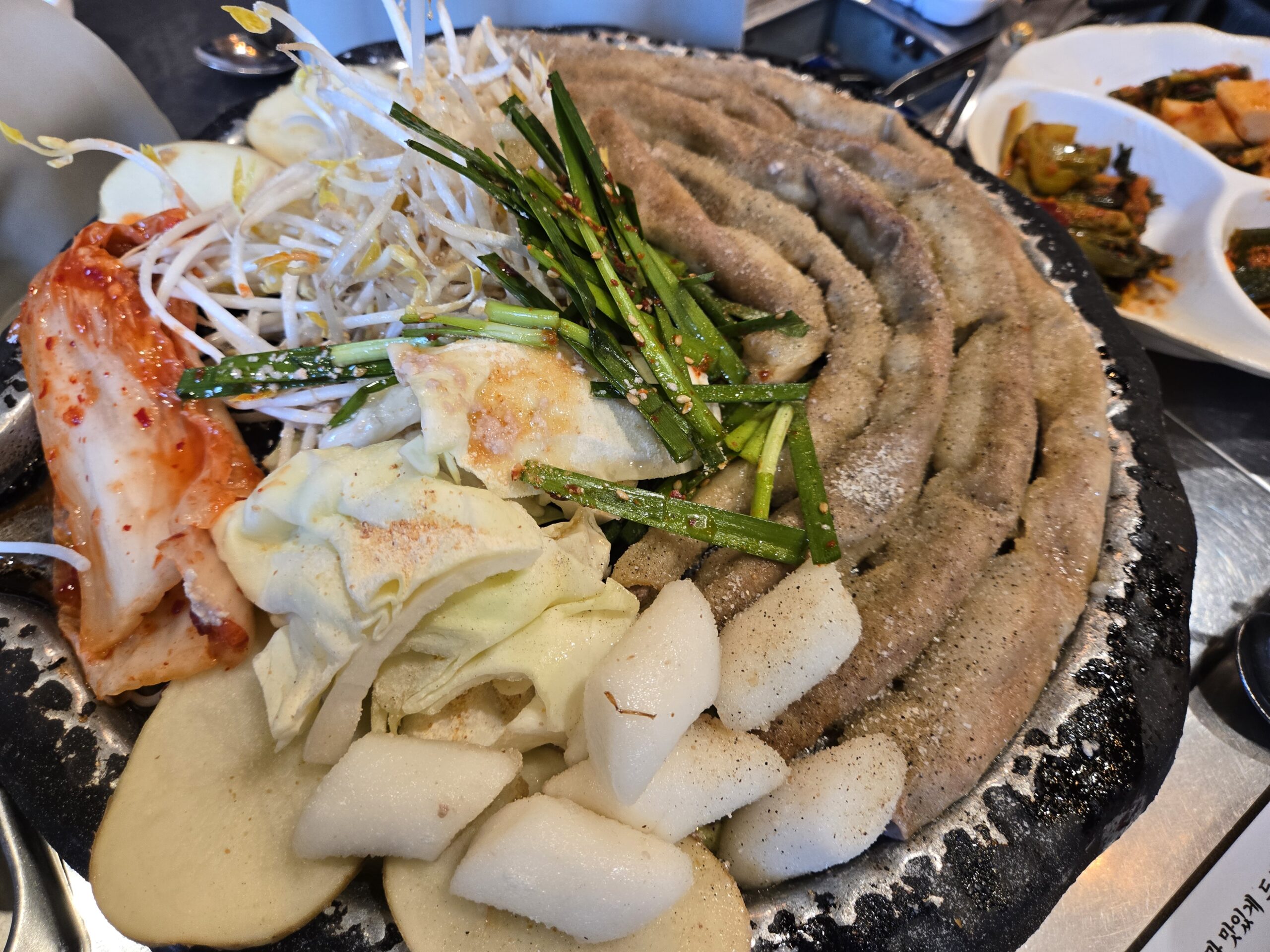 Raw beef gopchang setup on round stone plate with cabbage rice cake bean sprouts at Jinseong Hanu Gopchang