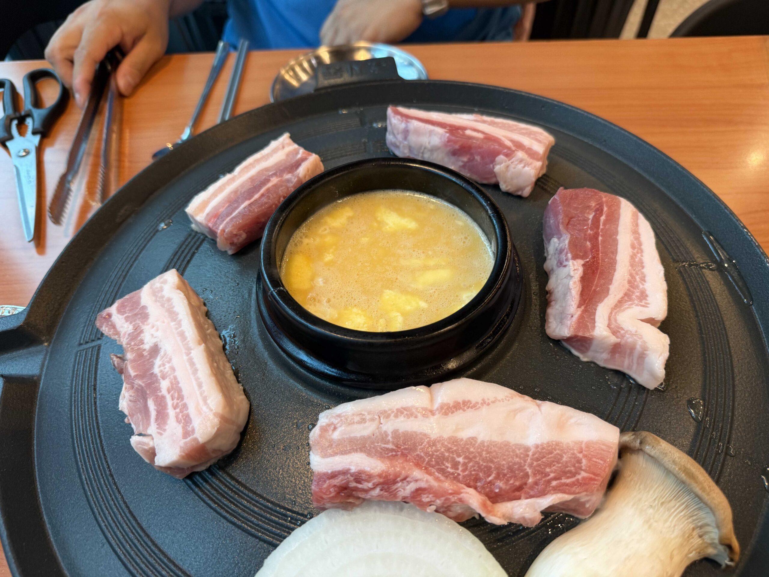 Raw pork belly arranged on the cauldron-lid griddle at Sottukkeong Samgyeopsal Hanam