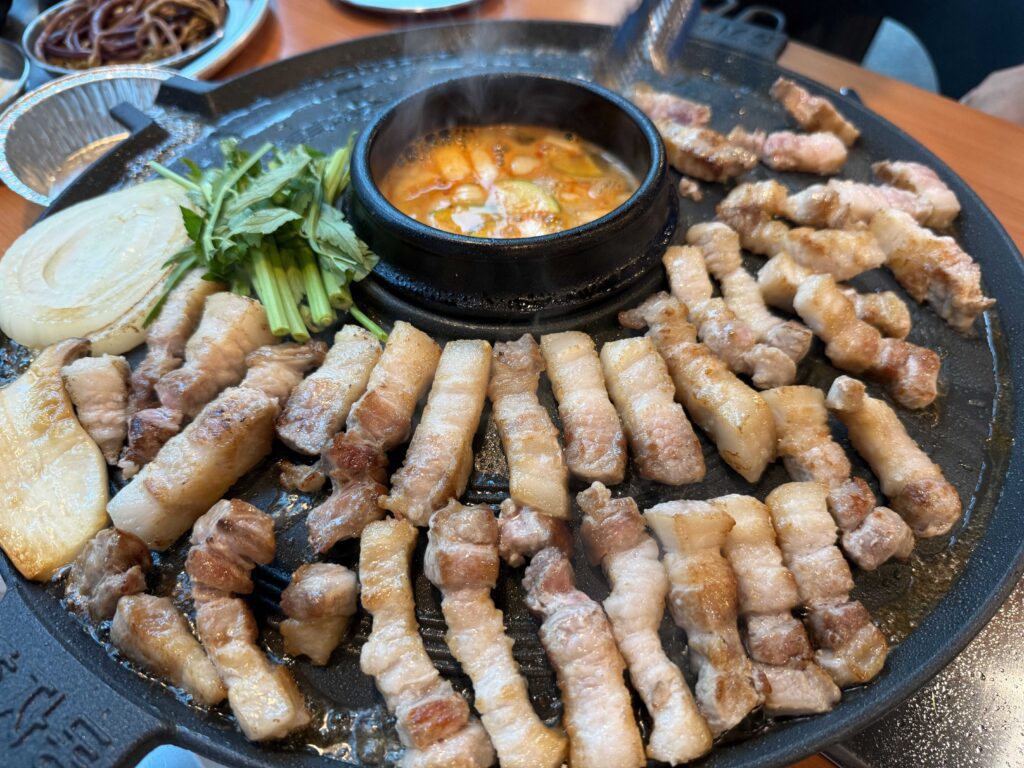 Cut pork belly cooking on the lid with minari and onion