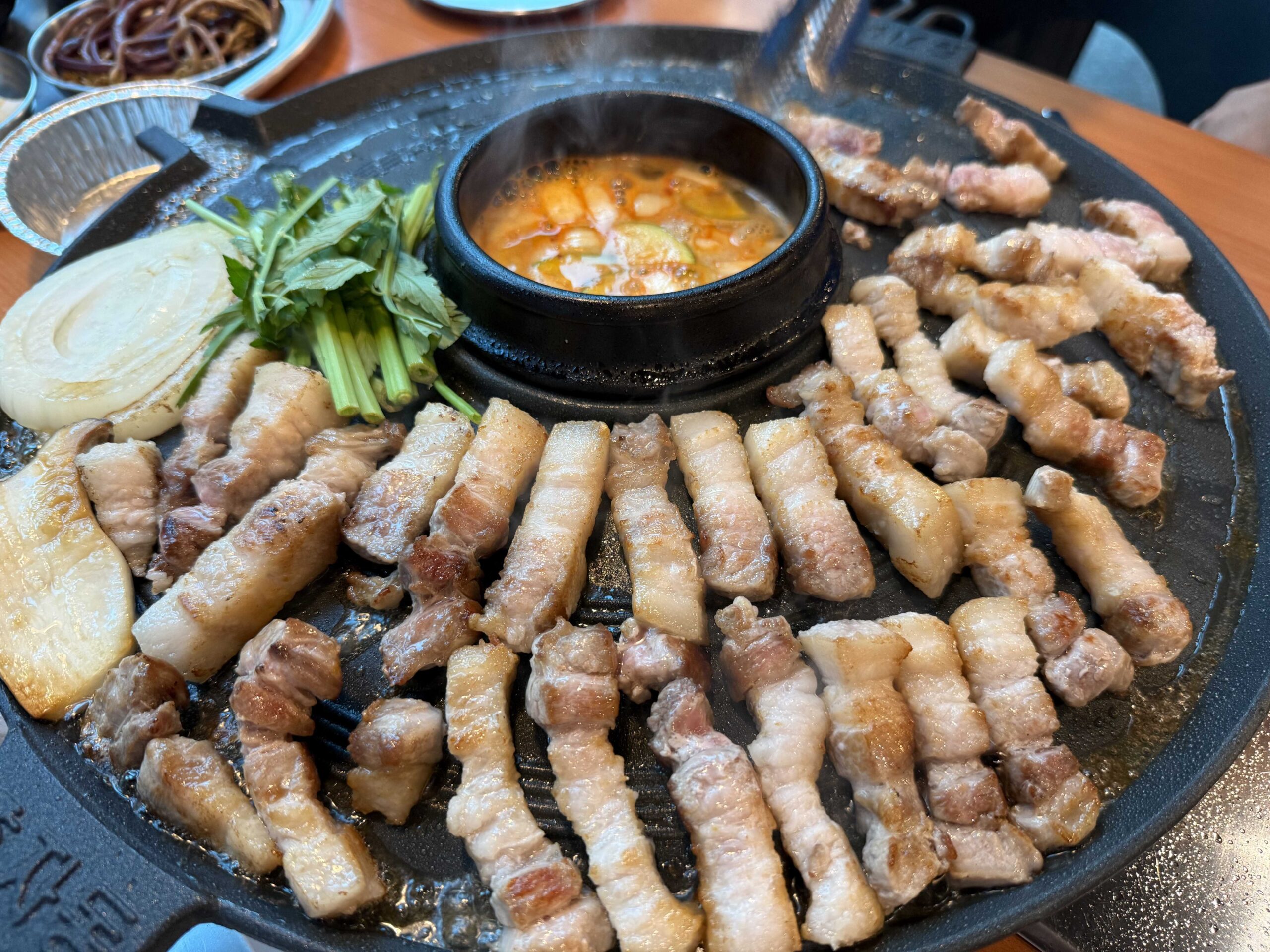 Grilled pork belly ringing the cauldron-lid griddle at Sottukkeong Samgyeopsal in Hanam