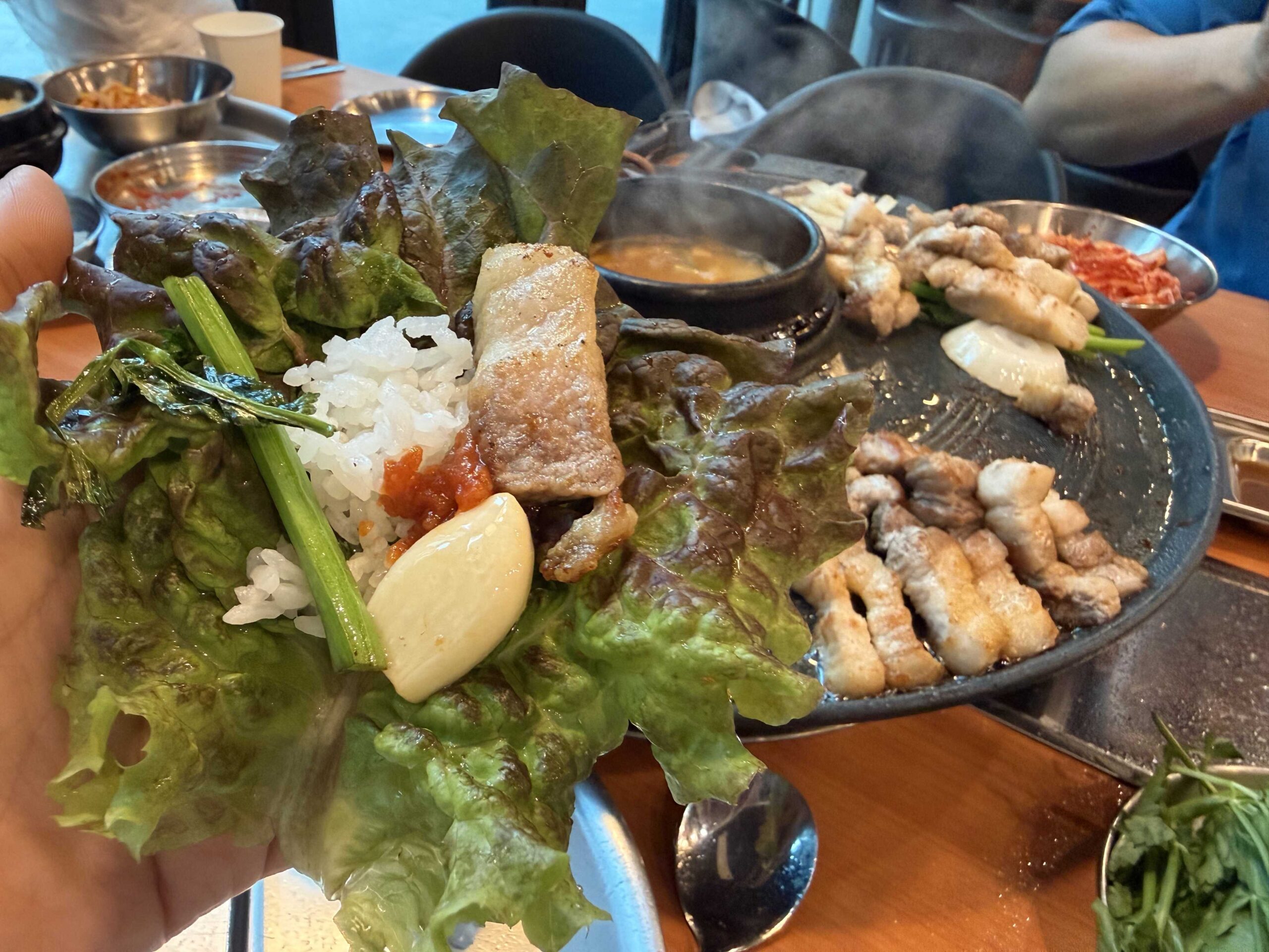 Lettuce wrap with pork belly and rice held over the griddle at Sottukkeong Samgyeopsal
