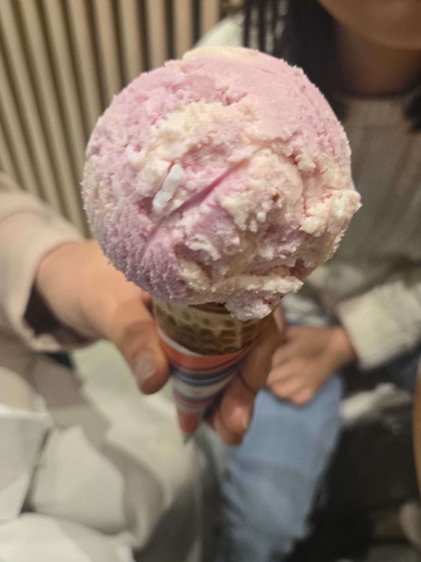 Berry single scoop on a waffle cone held up at Baskin-Robbins Wirye Traders